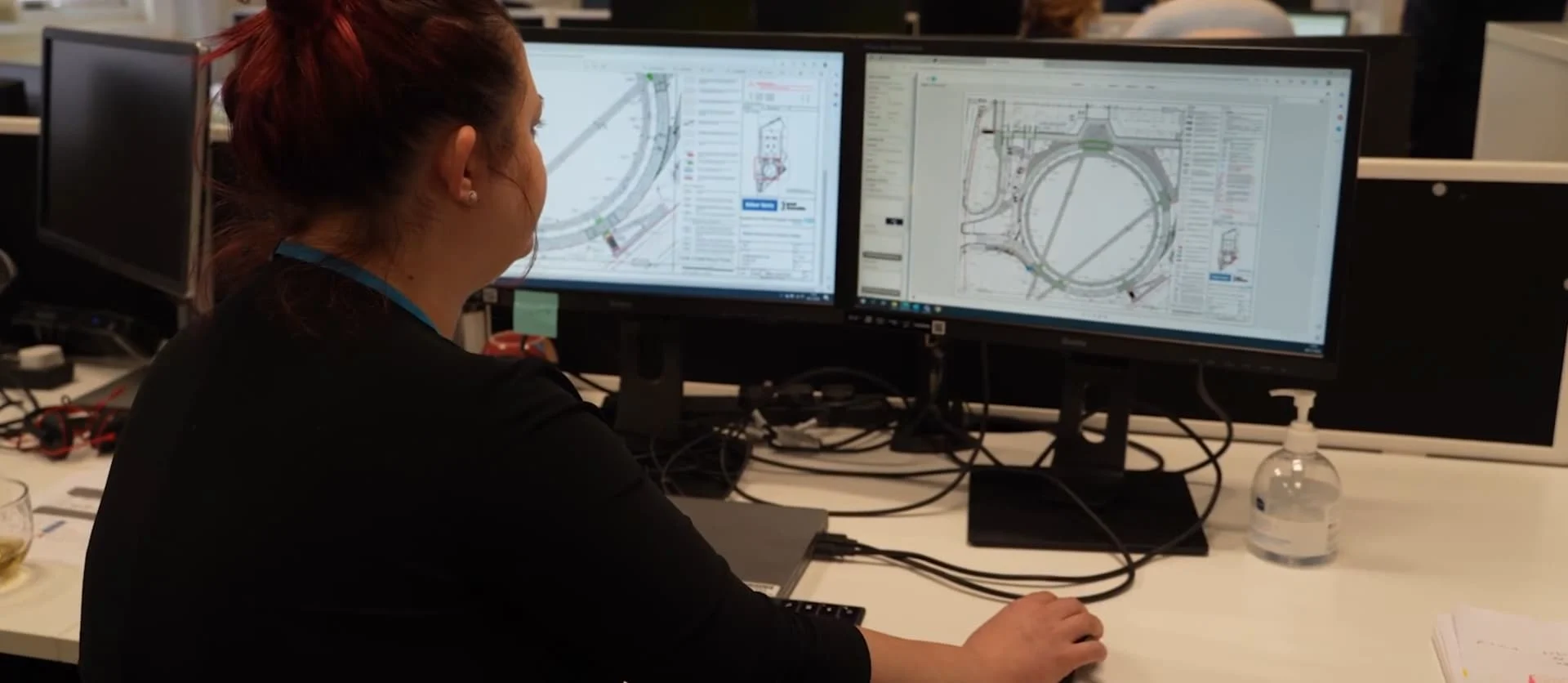 Engineer reviewing technical designs on dual monitors at a desk.