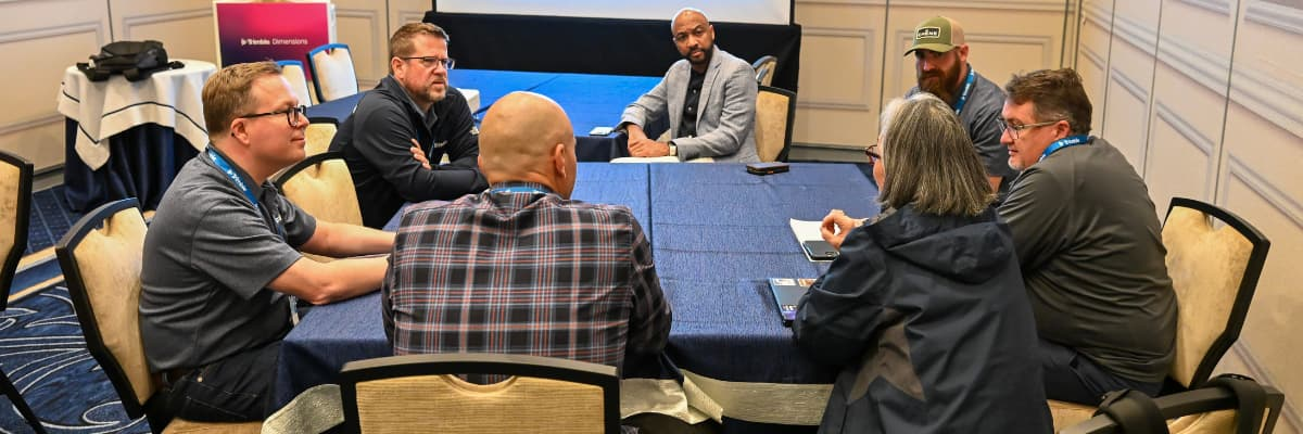 Seven construction contractors seated around a table discussing technology at the 2025 Trimble Dimensions user conference.