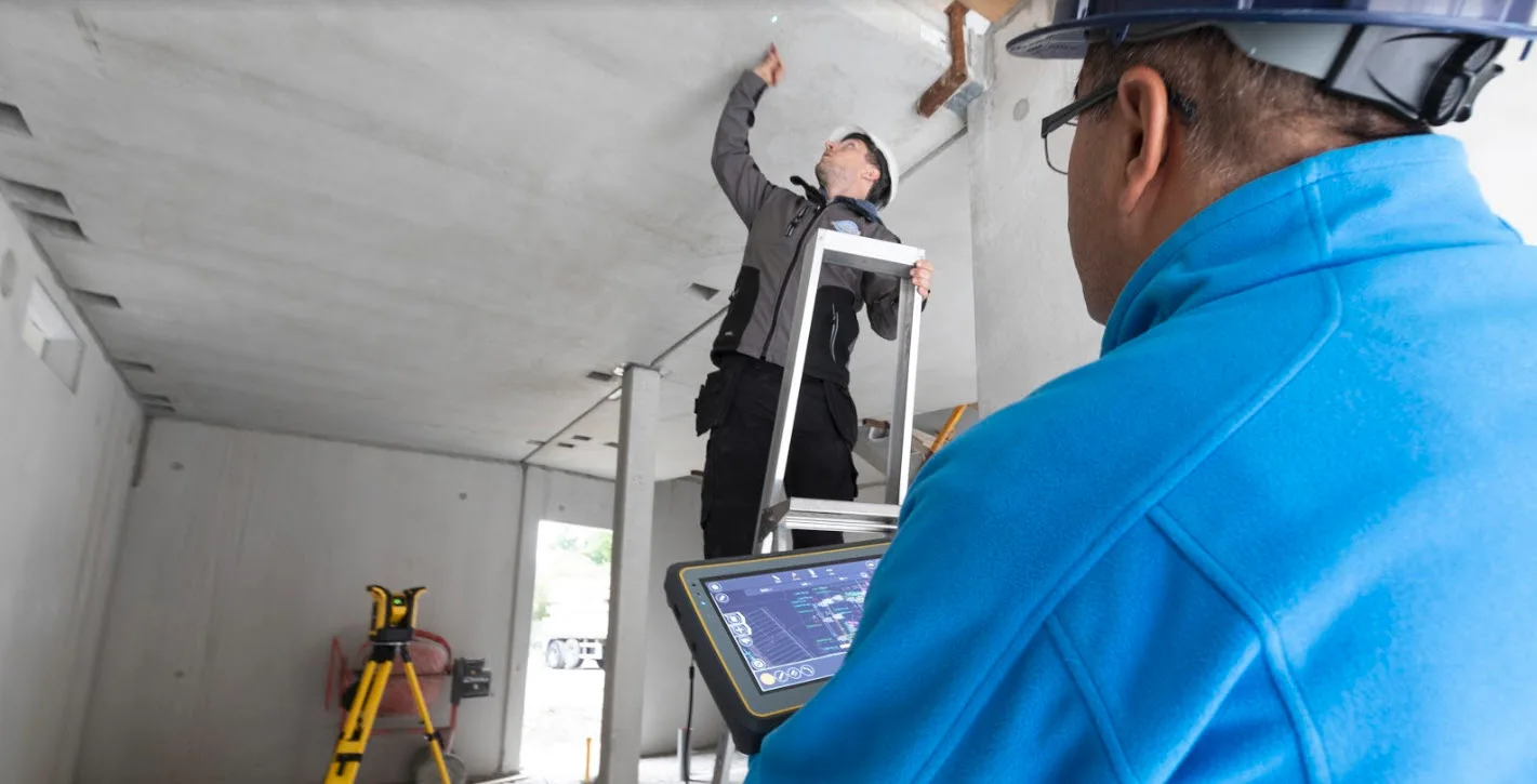 Construction workers on site using a tablet for project management.