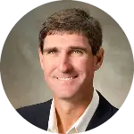 Headshot of a smiling man in a suit jacket and collared shirt.