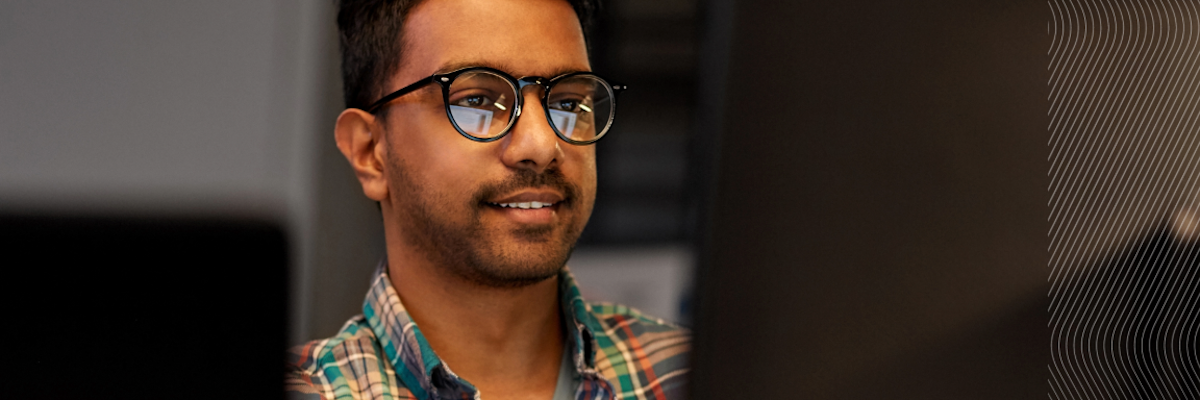 Person in plaid shirt working at a desk with computers