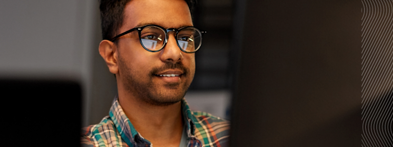 Person in plaid shirt working at a desk with computers