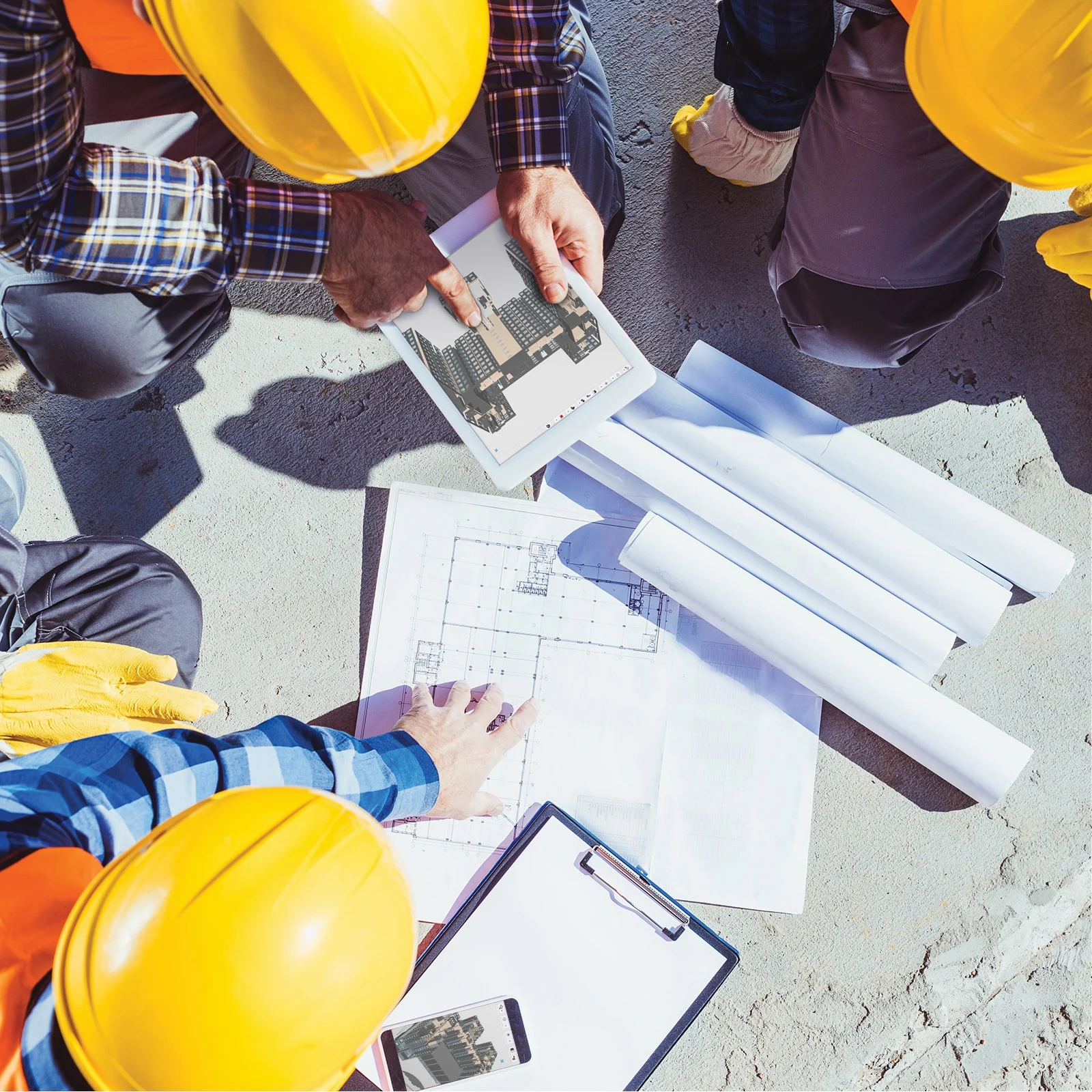 Construction workers collaborate on plans and a digital rendering of a building.