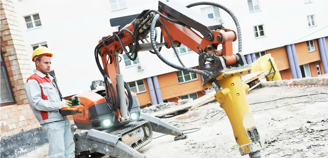 trabalhador da construção civil usa controlador para braço robótico em canteiro de obras 