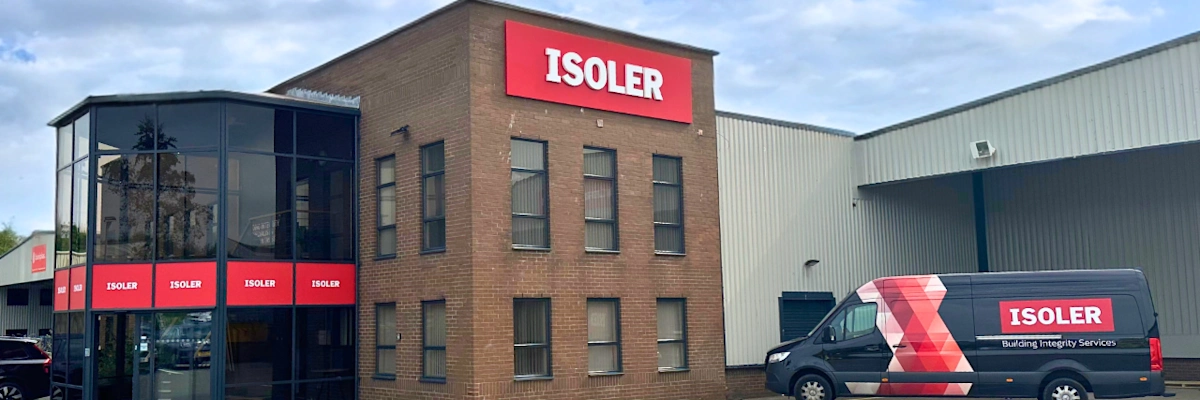 Brick office building with ISOLER signage and branded company van parked outside under cloudy sky.