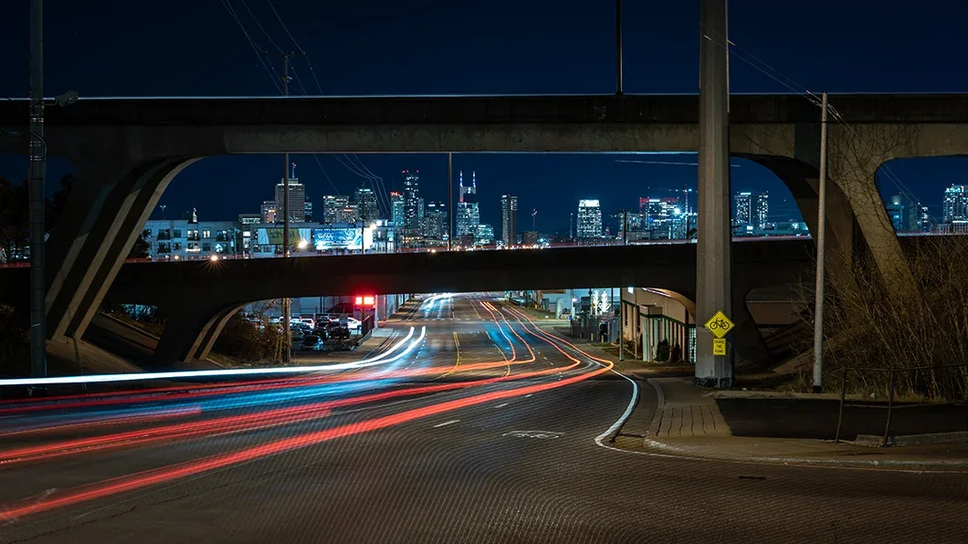 Night view of Nashville’s elevated highways framing the illuminated skyline and iconic AT&T Building with long-exposure light trails.