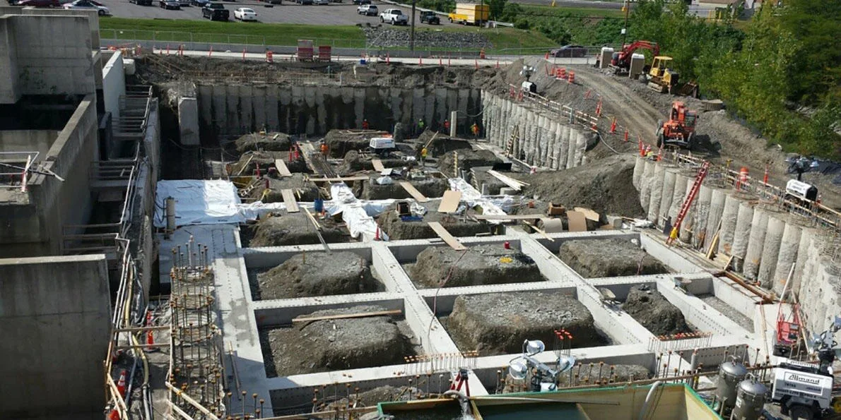 Construction site showing the foundations of a building under construction with heavy machinery present.