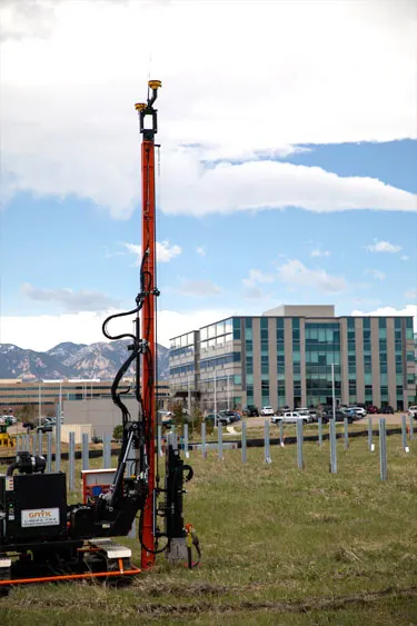 Pile driver installing piles for solar farm