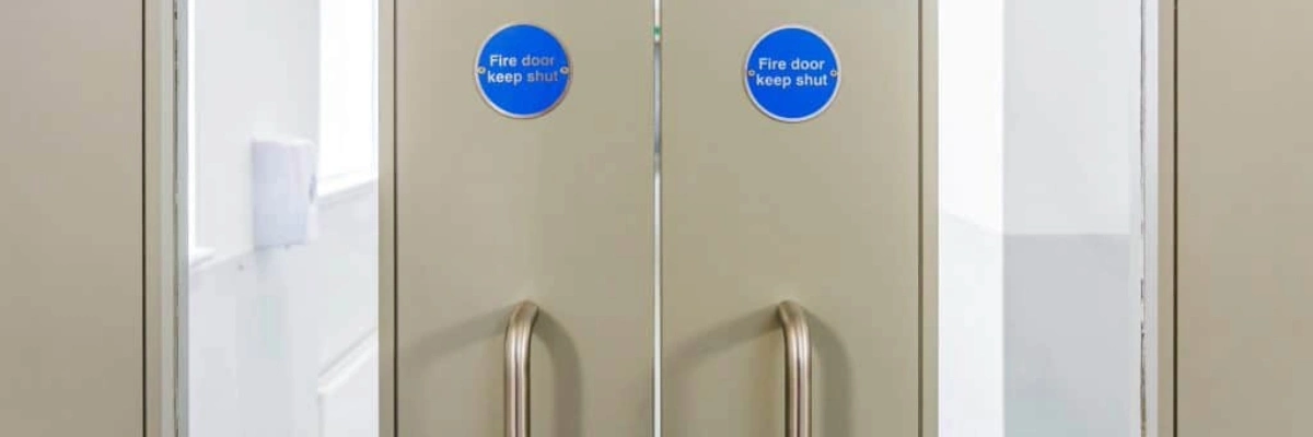 Double doors with "Fire door keep shut" signs and metal handles