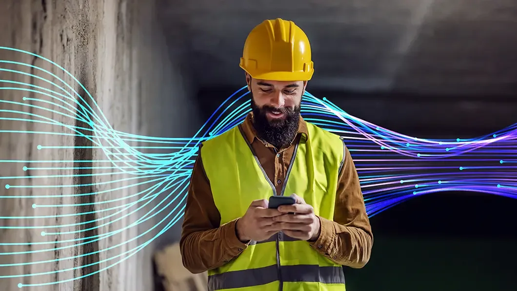 Worker in safety gear using a smartphone with digital wave graphics.