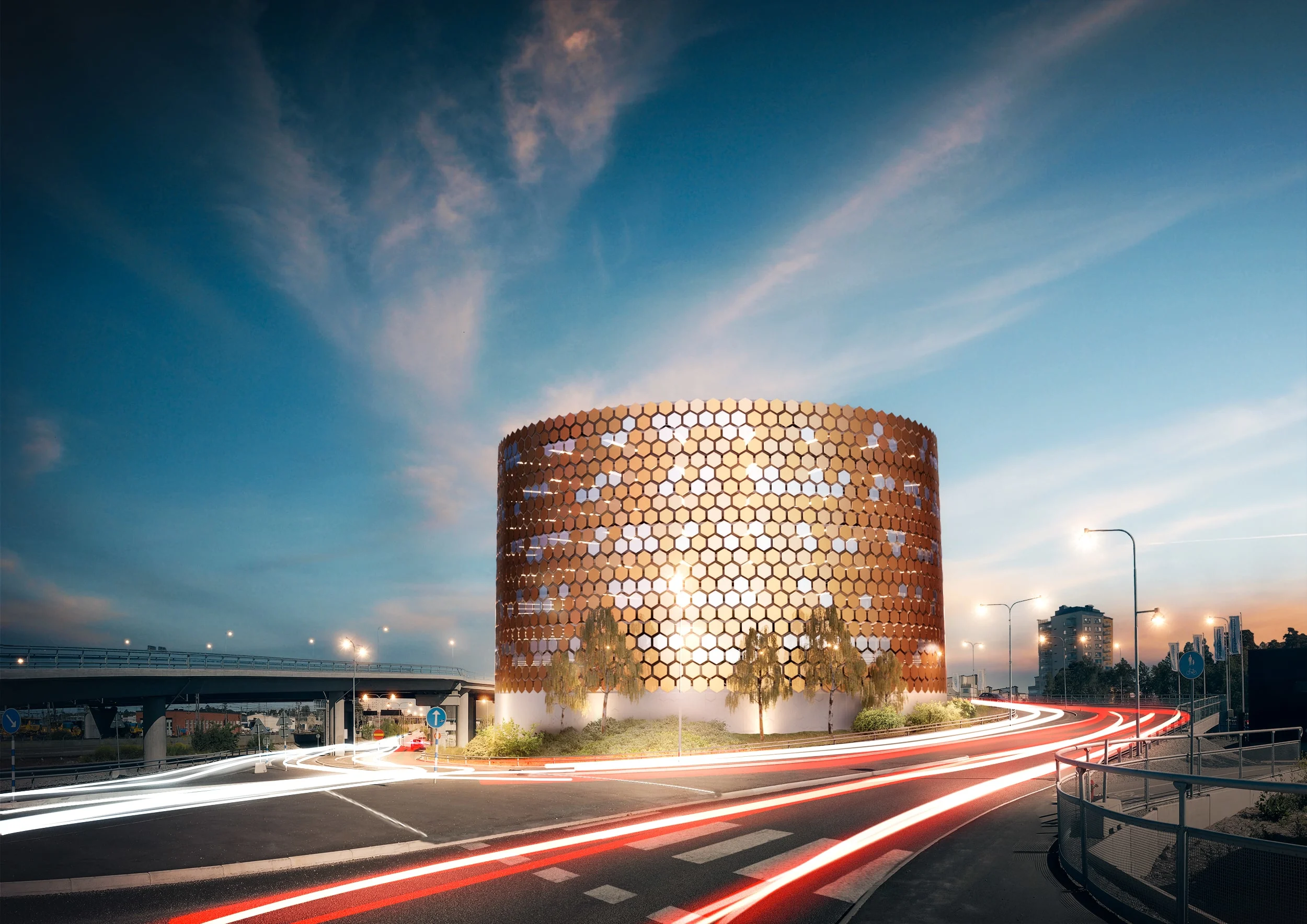 Modern circular building with honeycomb facade at dusk, with light trails from cars on the road.