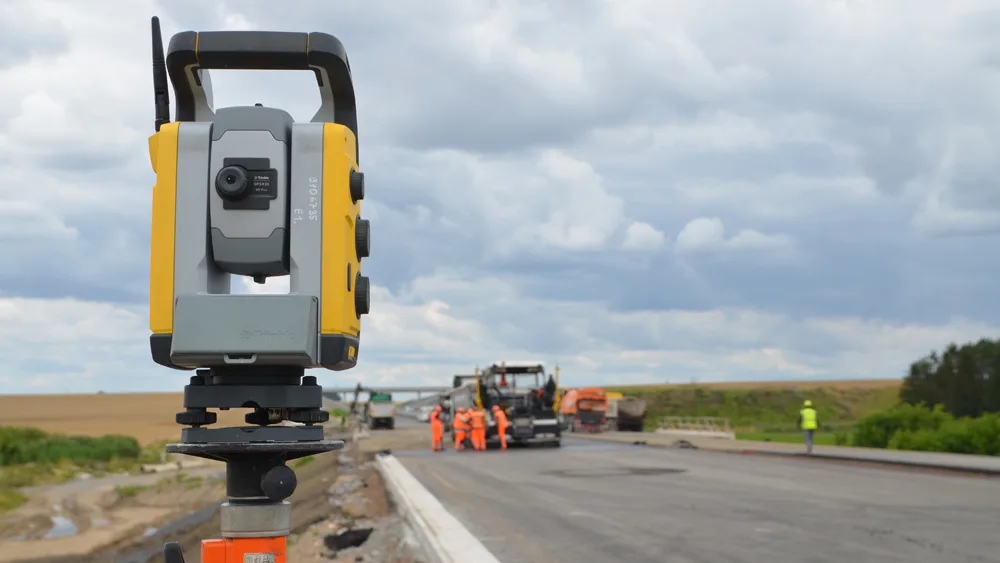 Total station with paver working in the background