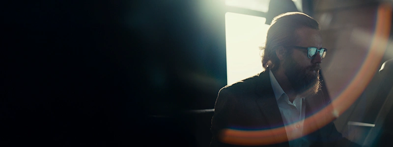 Joseph Fulco, with brushed back brown hair and glasses and backlit by a window, focuses on his screen.