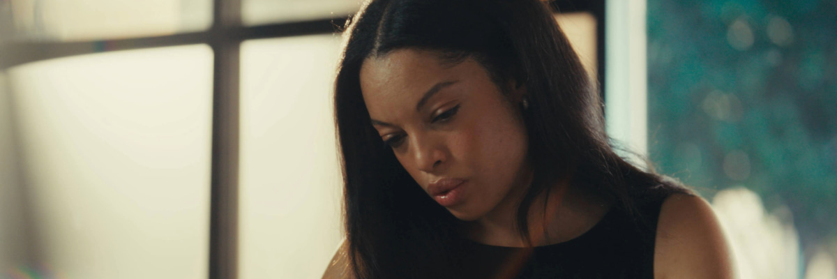 Taryn holds a pen and book in hand at her workspace.