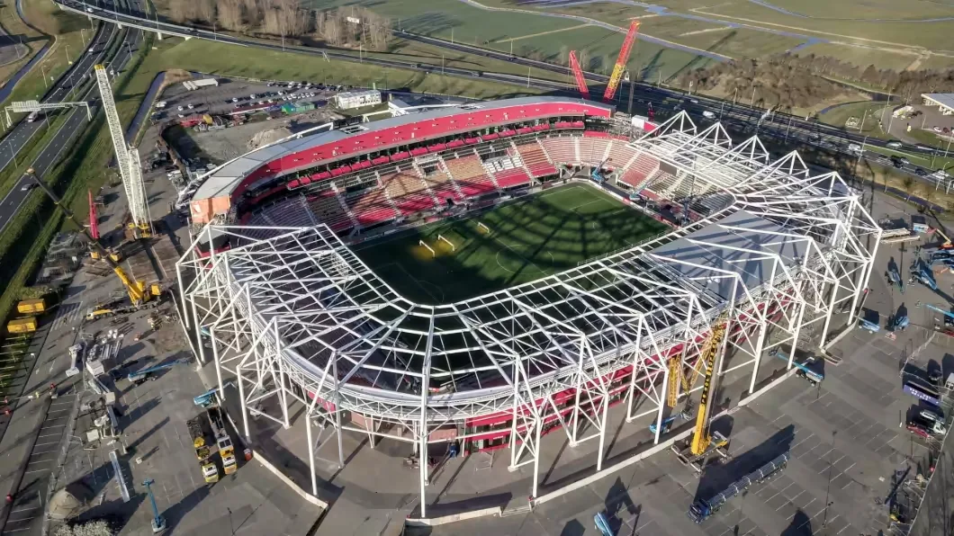 Aerial view of a football stadium under construction, with cranes and scaffolding surrounding the partially completed structure.