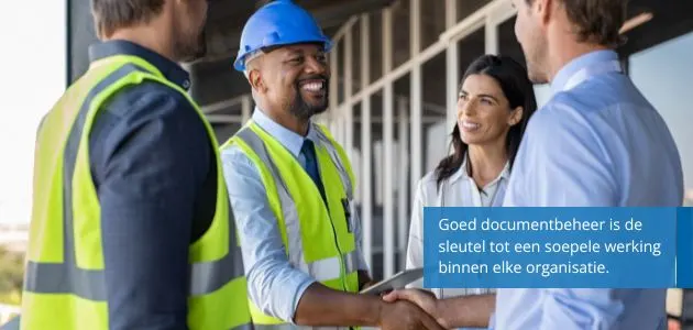 A diverse group of four professionals are shaking hands, with two wearing safety vests and hard hats, suggesting a construction or industrial setting.