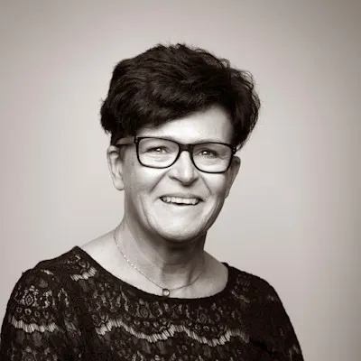 Sepia-toned headshot of Marie Laven wearing glasses and a black lace top.