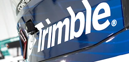 Close-up of a metallic blue vehicle featuring the white Trimble logo and a black banner with the word CONFIDENCE.