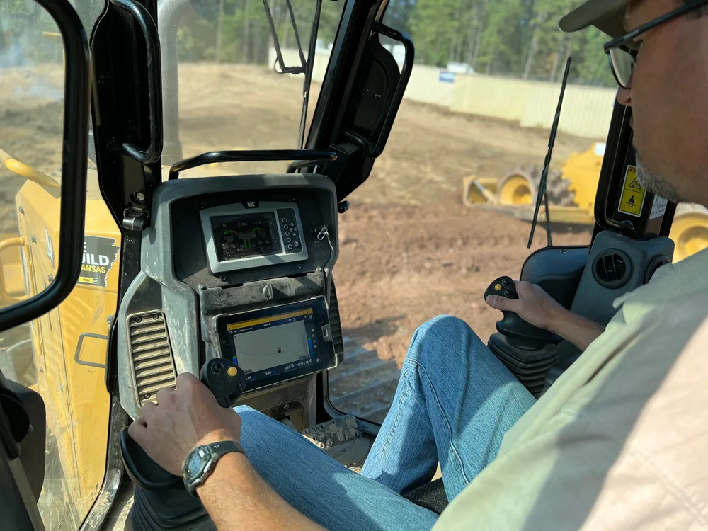 Operator's view from inside a bulldozer cabin with control panel and GPS display.