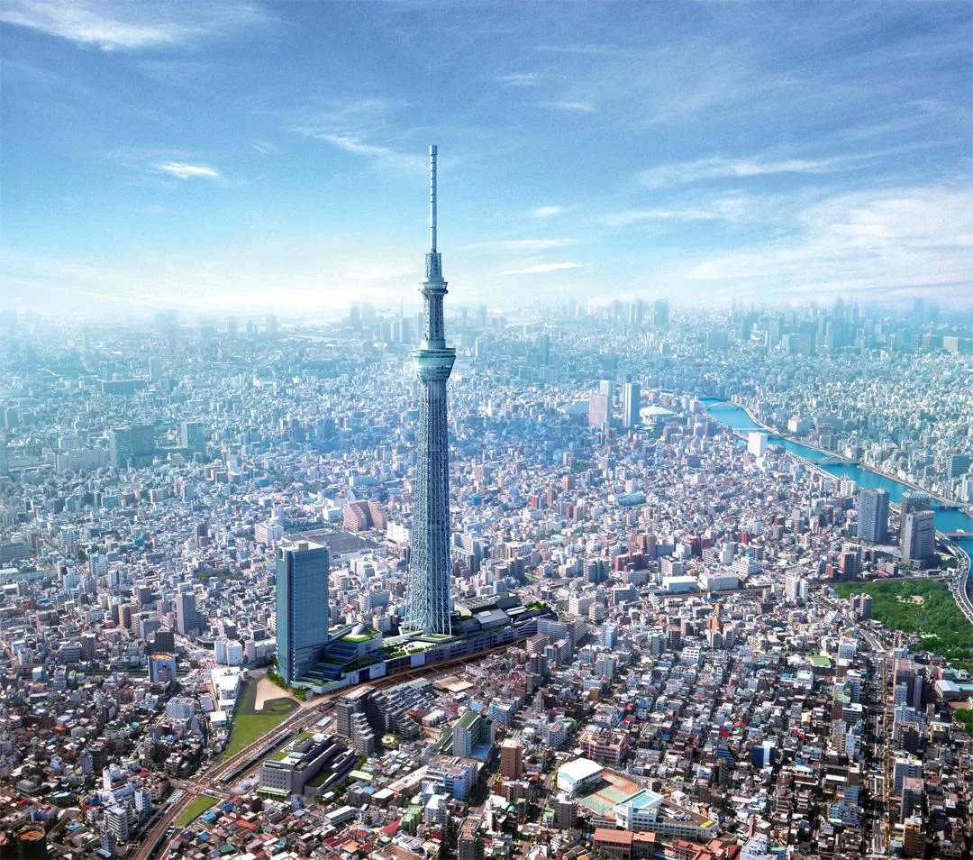 An aerial view of the Tokyo Skytree, a broadcasting and observation tower, towering over the dense cityscape of Tokyo, Japan.