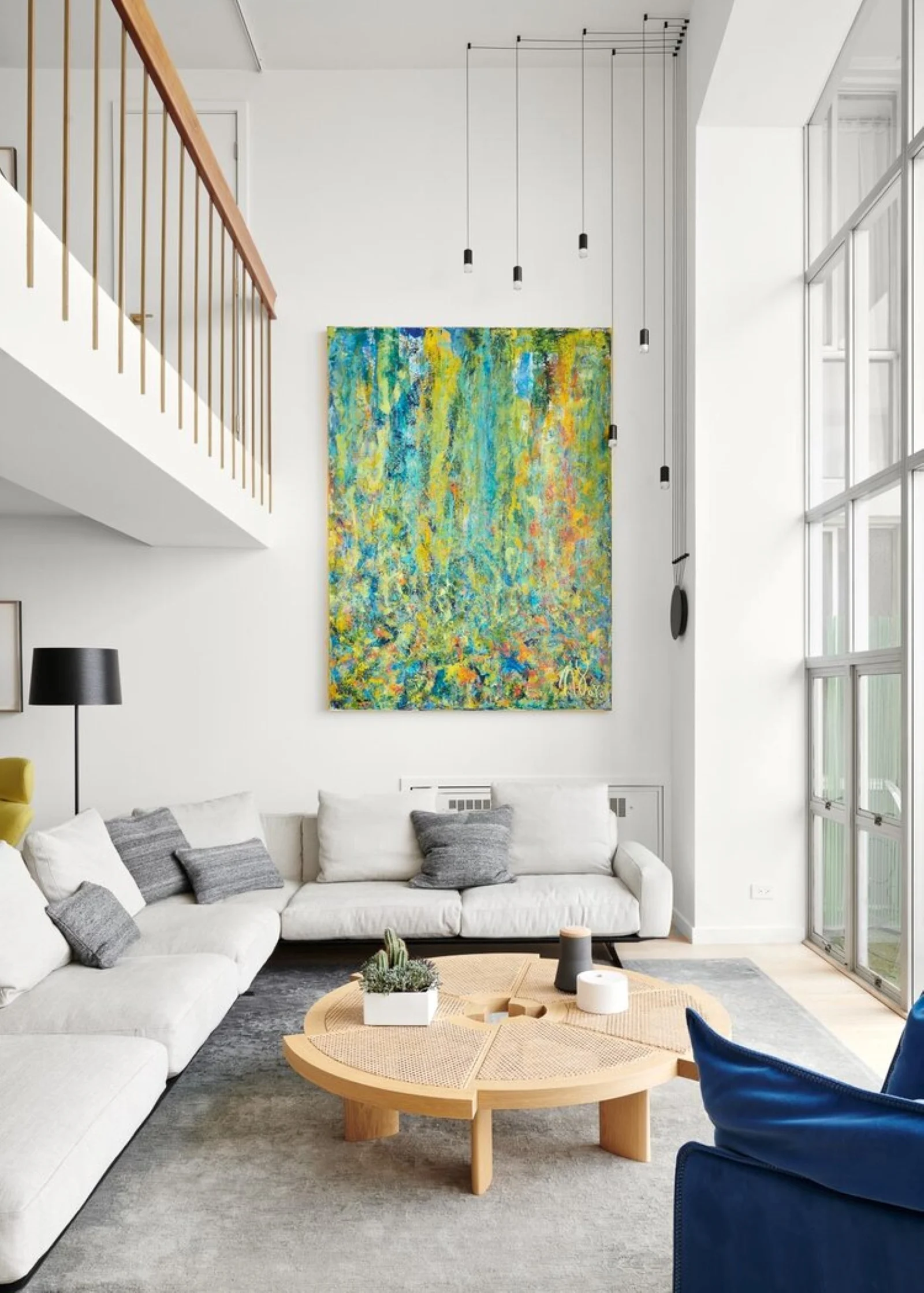 Bright abstract artwork hangs above a sectional sofa in a modern living room.