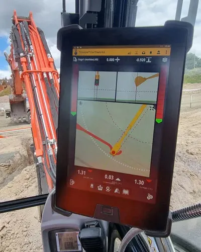 Digital navigation display mounted in construction equipment showing GPS mapping and positioning data at a worksite.