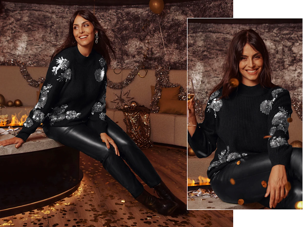 Ein Model in einer einer Party Umgebung trägt einen schwarzen Pullover mit Pailletten und eine
schmale, schwarze Lederimitat-Hose.