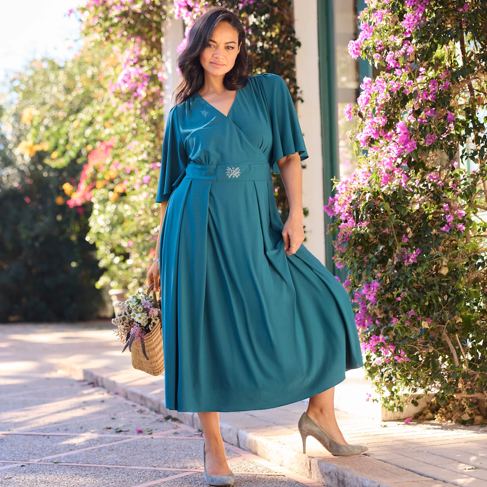 Model in tannen grünem Abendkleid mit Schmuckelement in der Taille