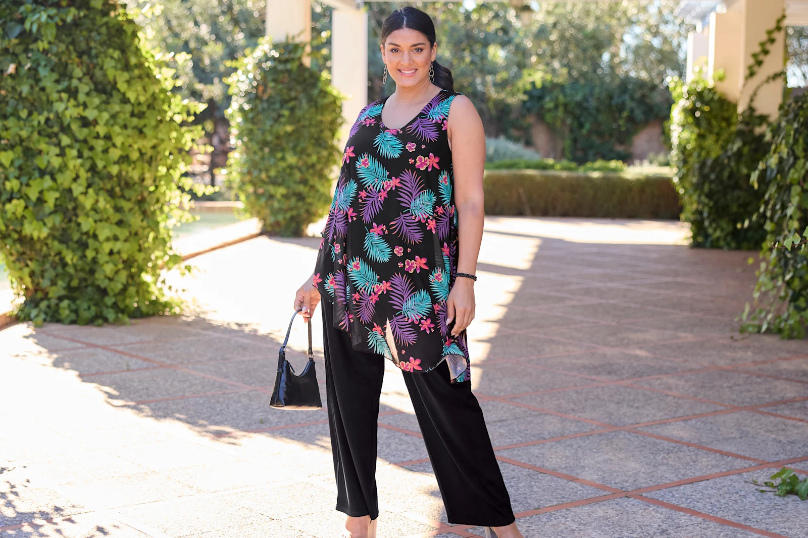 Model in Jumpsuit mit schwarzer Hose und bunt gemustertem weiten Chiffonoberteil