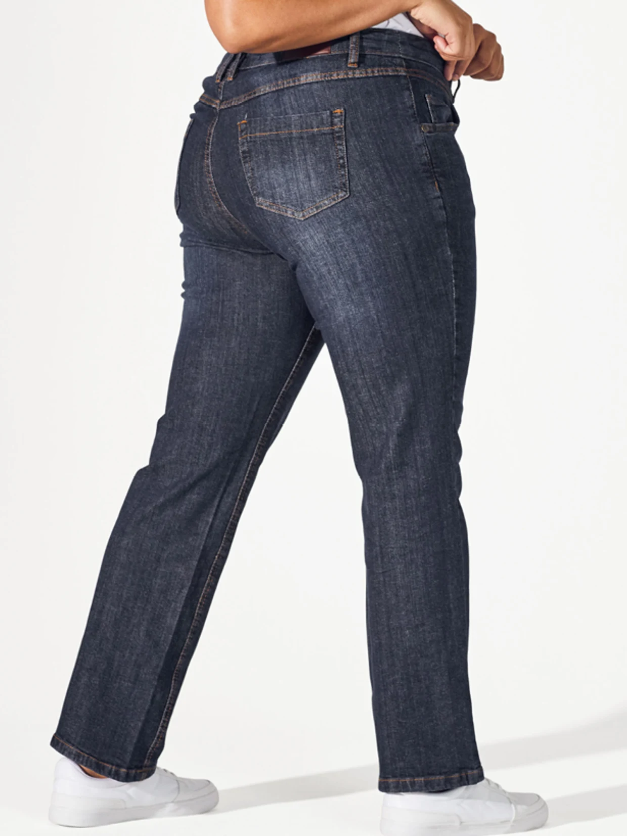 Frau steht seitlich und zeigt ihre gerade Jeans