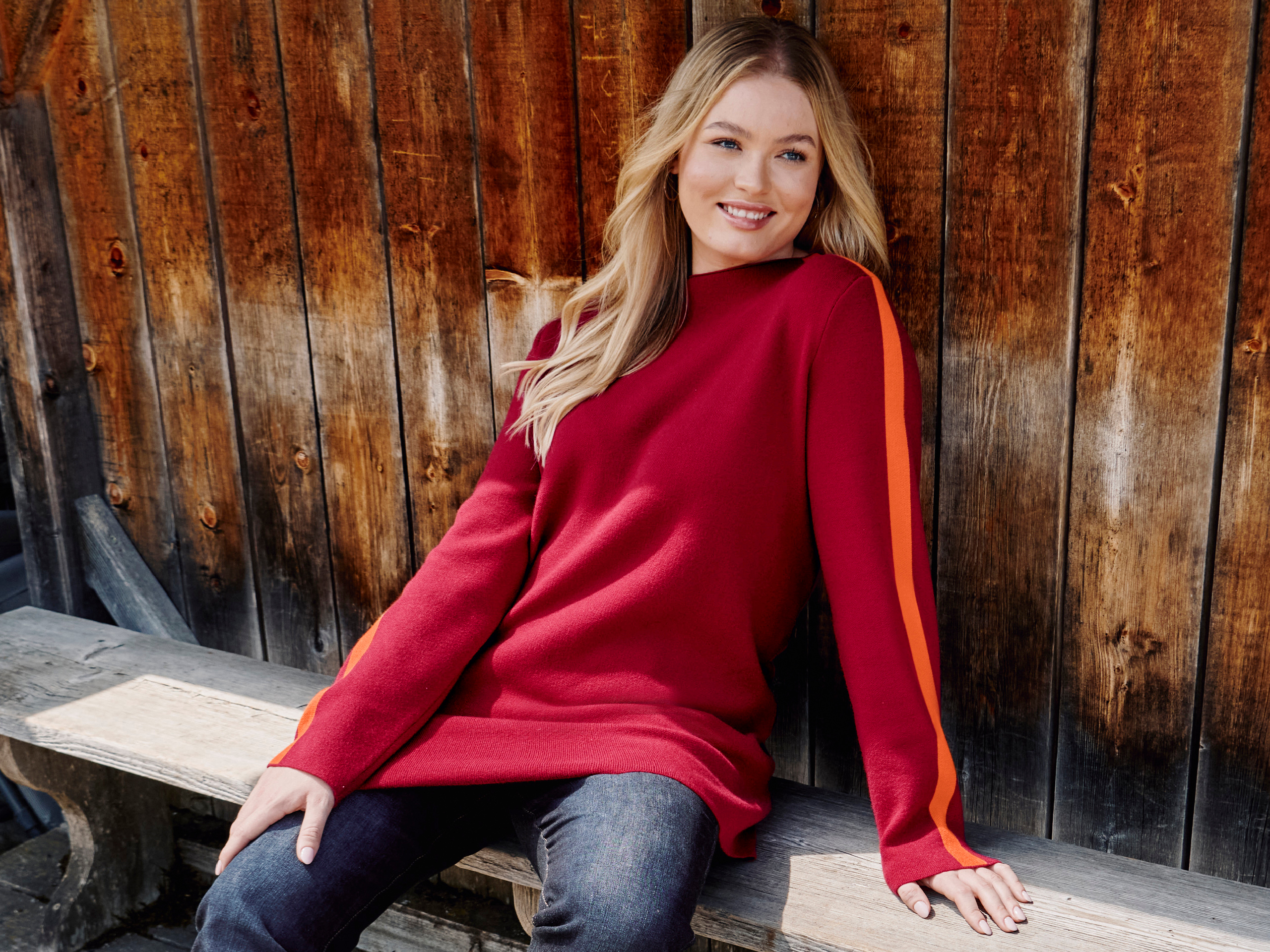 Model in kirschrotem Pulli mit orangen Streifen am Ärmel