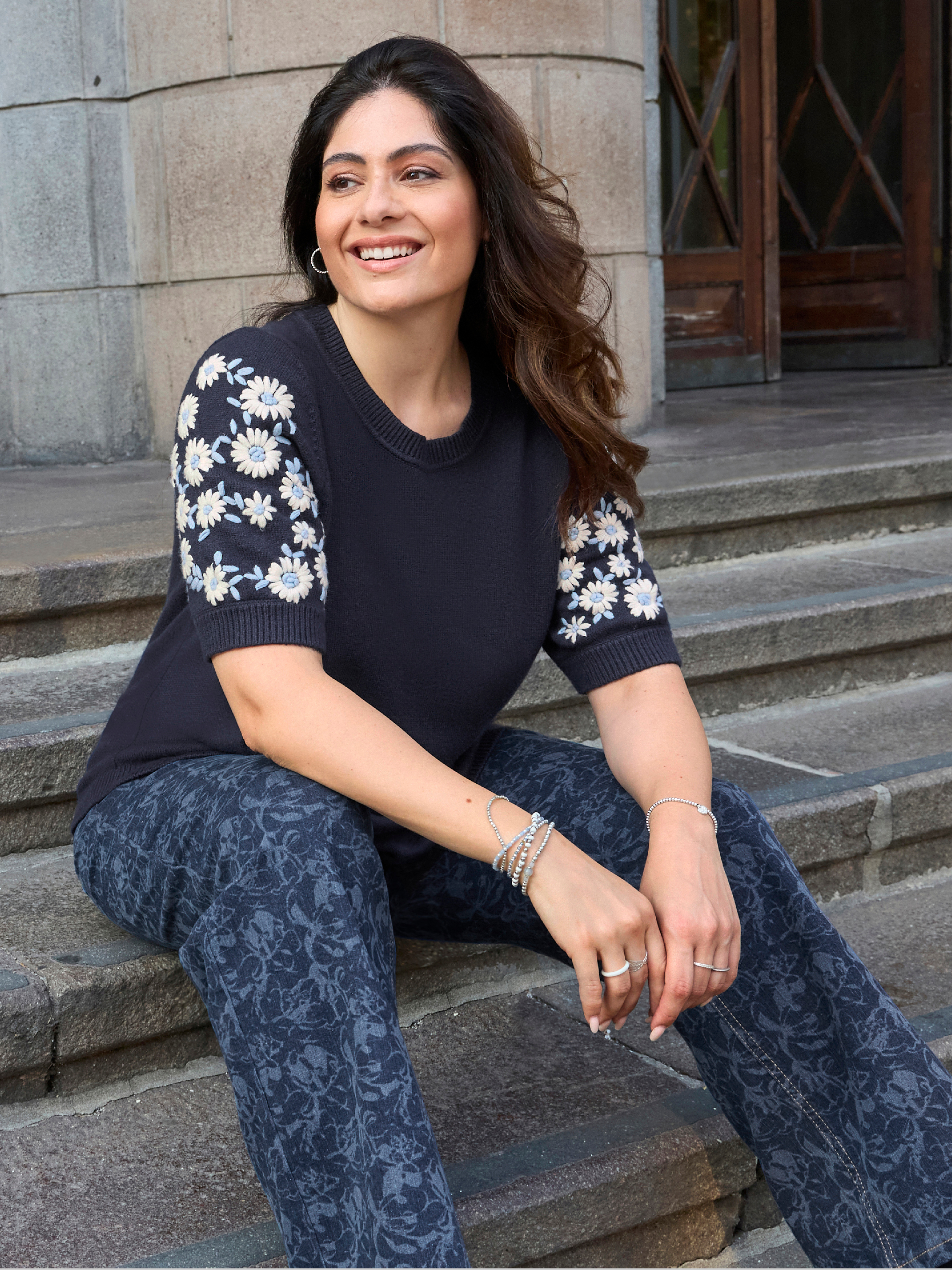 Model mit marinefarbenem Kurzampulli mit Ärmeln mit gummierten Blüten und floral bedruckter Jeans