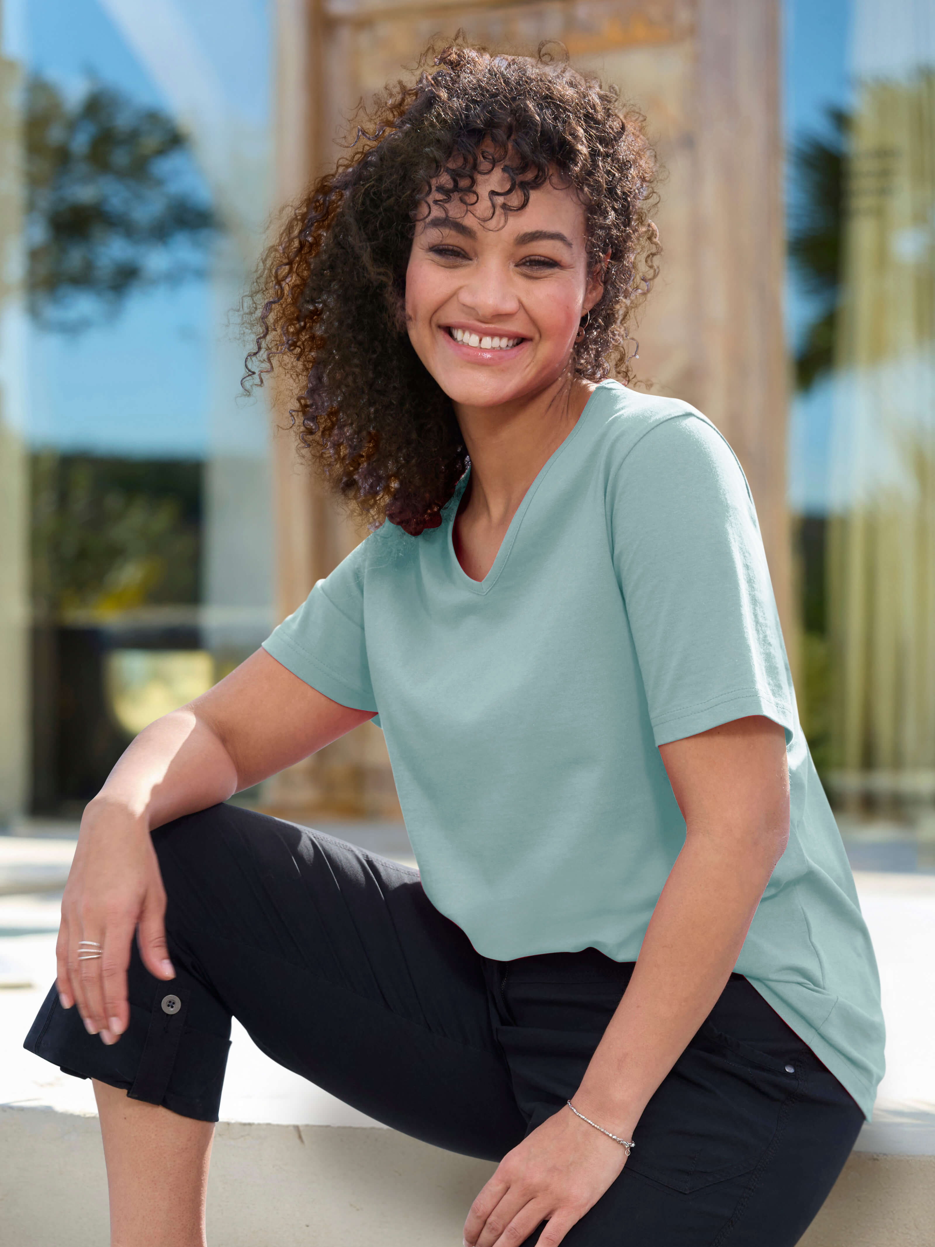 Ein Model in einer Urlaubsumgebung trägt trägt eine kalkmint farbenes Shirt. 