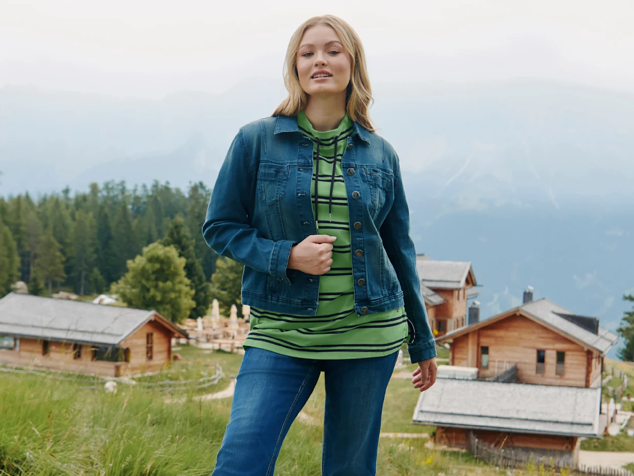 Model mit Jeansjacke über grünem gestreiften Sweatshirt und Jeans Model mit Jeansjacke über grünem gestreiften Sweatshirt und Jeans