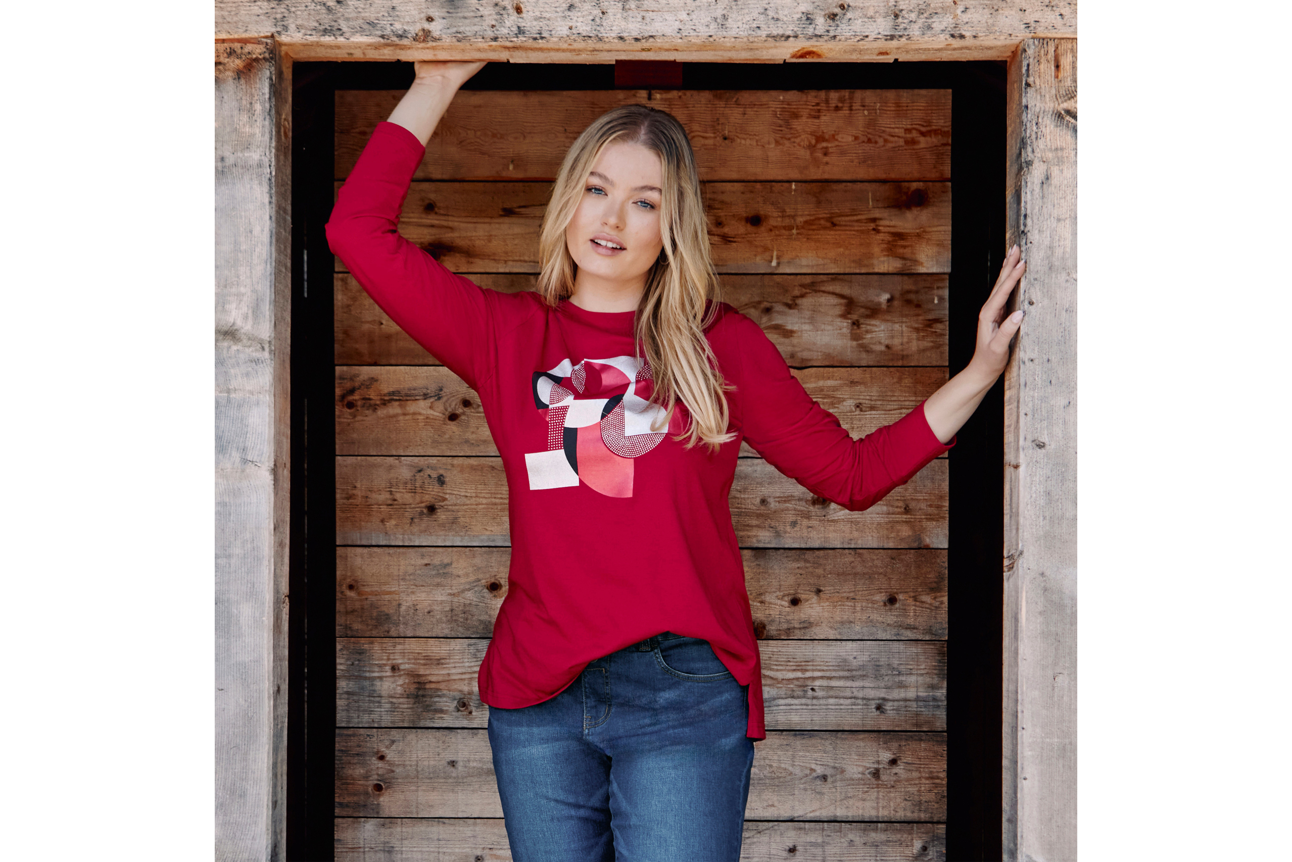 Model mit kirschrotem Langarmshirt mit graphischem Glanzaufdruck