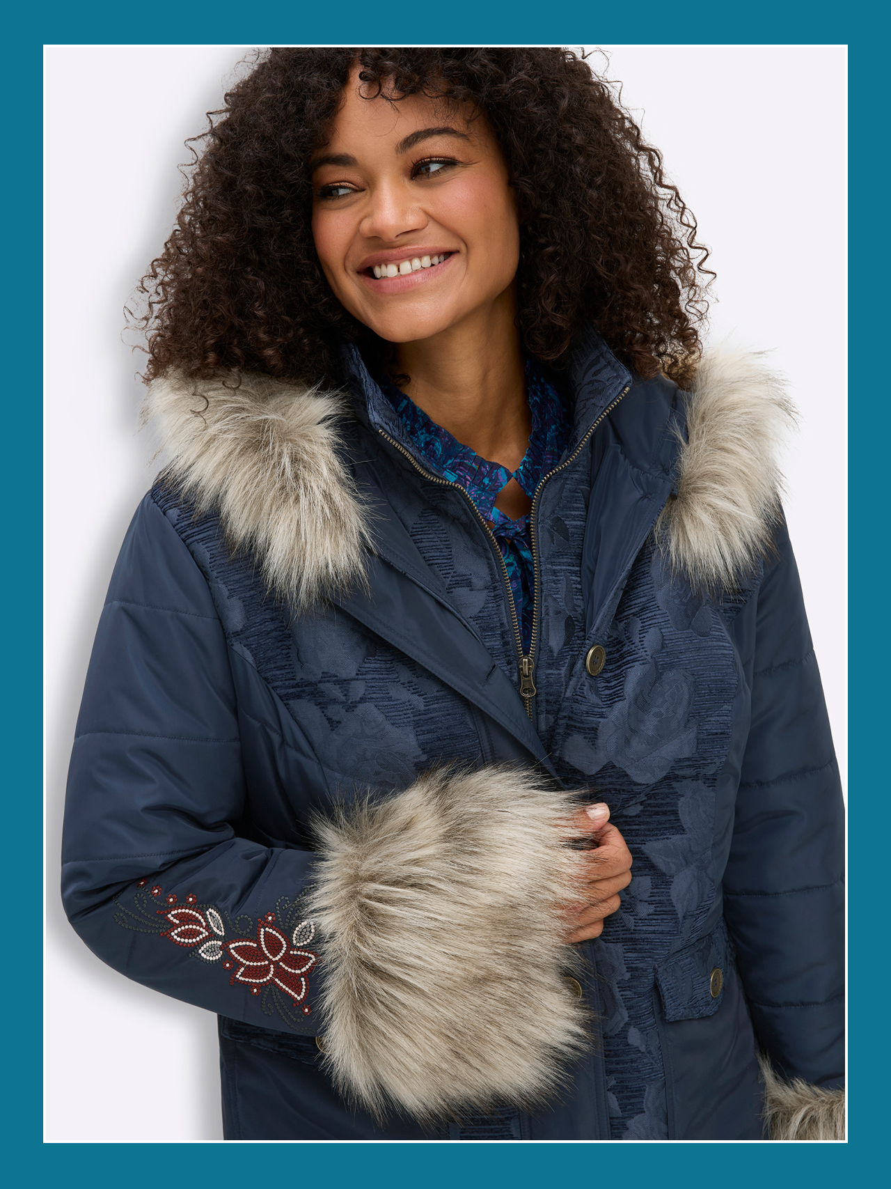 Ein Model trägt eine dunkelblaue Winterjacke  mit Jacquardmuster, Blumenstickereien und Fell-Imitat.