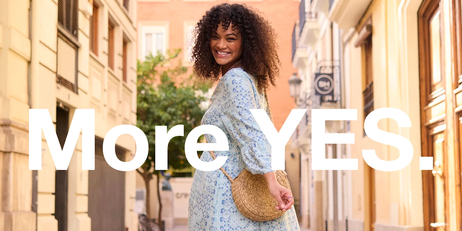 Werbebanner mit Model in hellblau bedrucktem Maxikleid und Text: More YES.