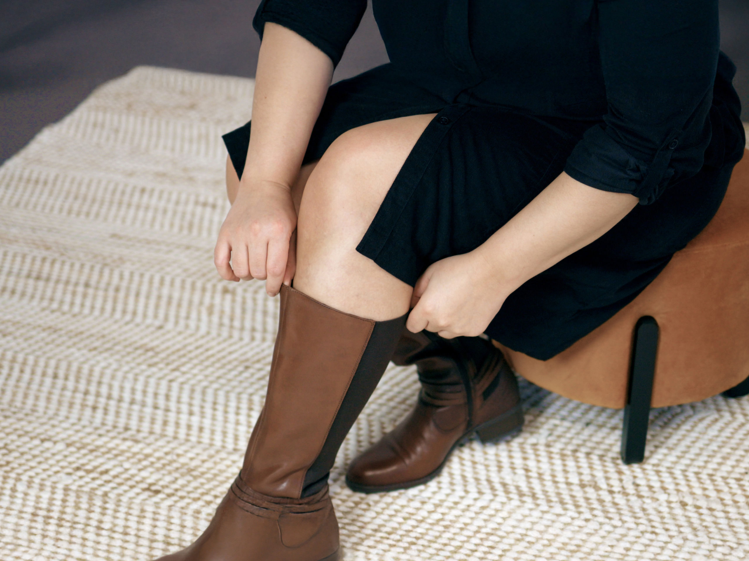 Frau zieht im Sitzen einen Weitschaftstiefel an 