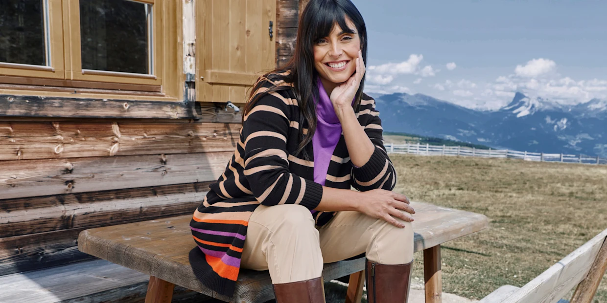 Model in gestreiftem Cardigan in schwarz-beige mit orange-lila Streifen am Saum