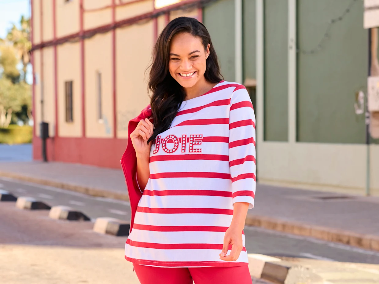 Ein Model trägt ein weiß-rot gestreiftes Shirt mit dem Aufdruck JOIE und eine rote Jeans. Daneben der Text: Die neue Kollektion. Langsam wird es Frühling!
