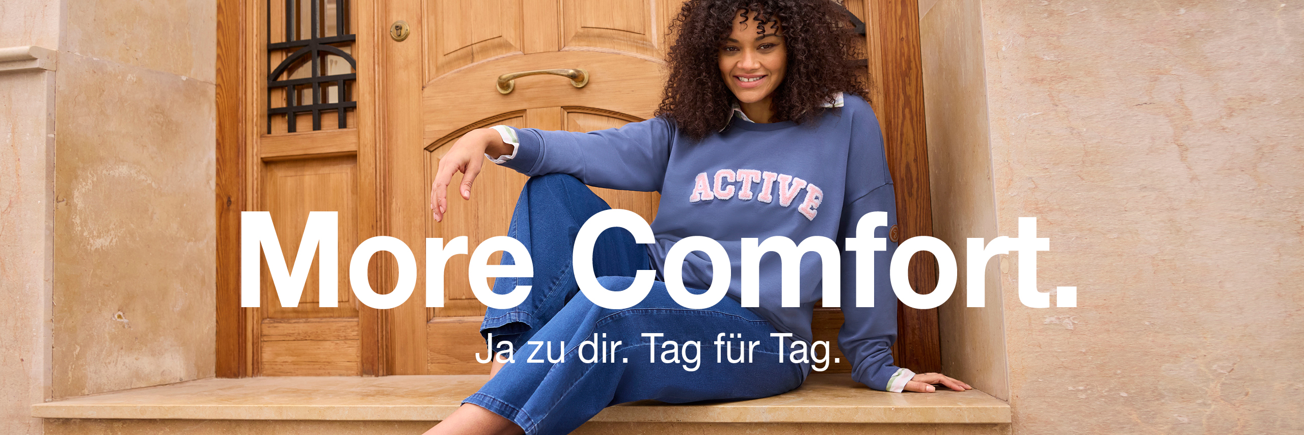 Werbebanner mit Model in Sweatshirt und Jeans mit Text: More Comfort. Ja zu dir. Tag für Tag.