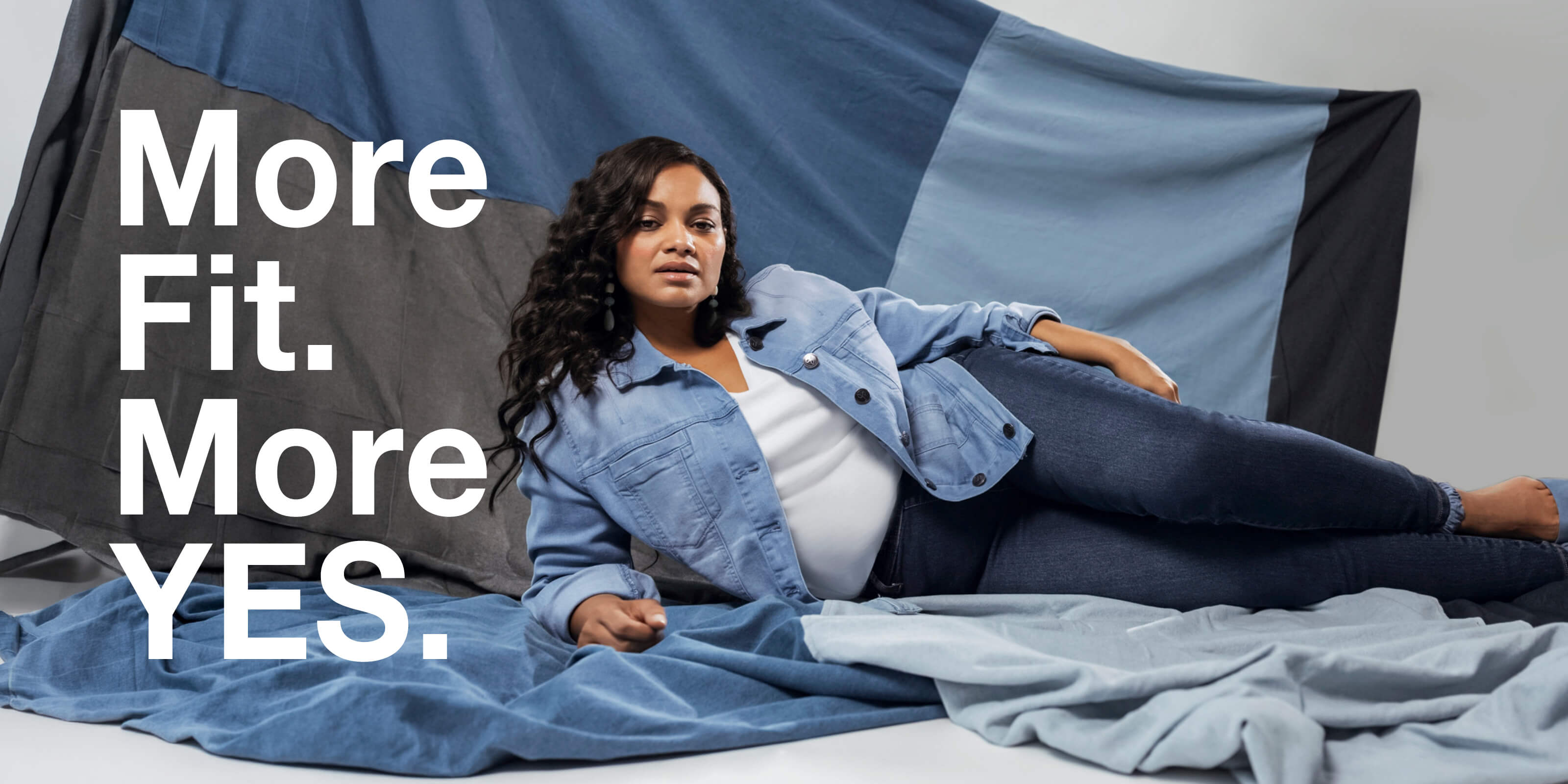 Ein Model trägt eine Jeansjacke in light blue und eine Jeans in dark-blue. Daneben der Text: More Fit. More yes.