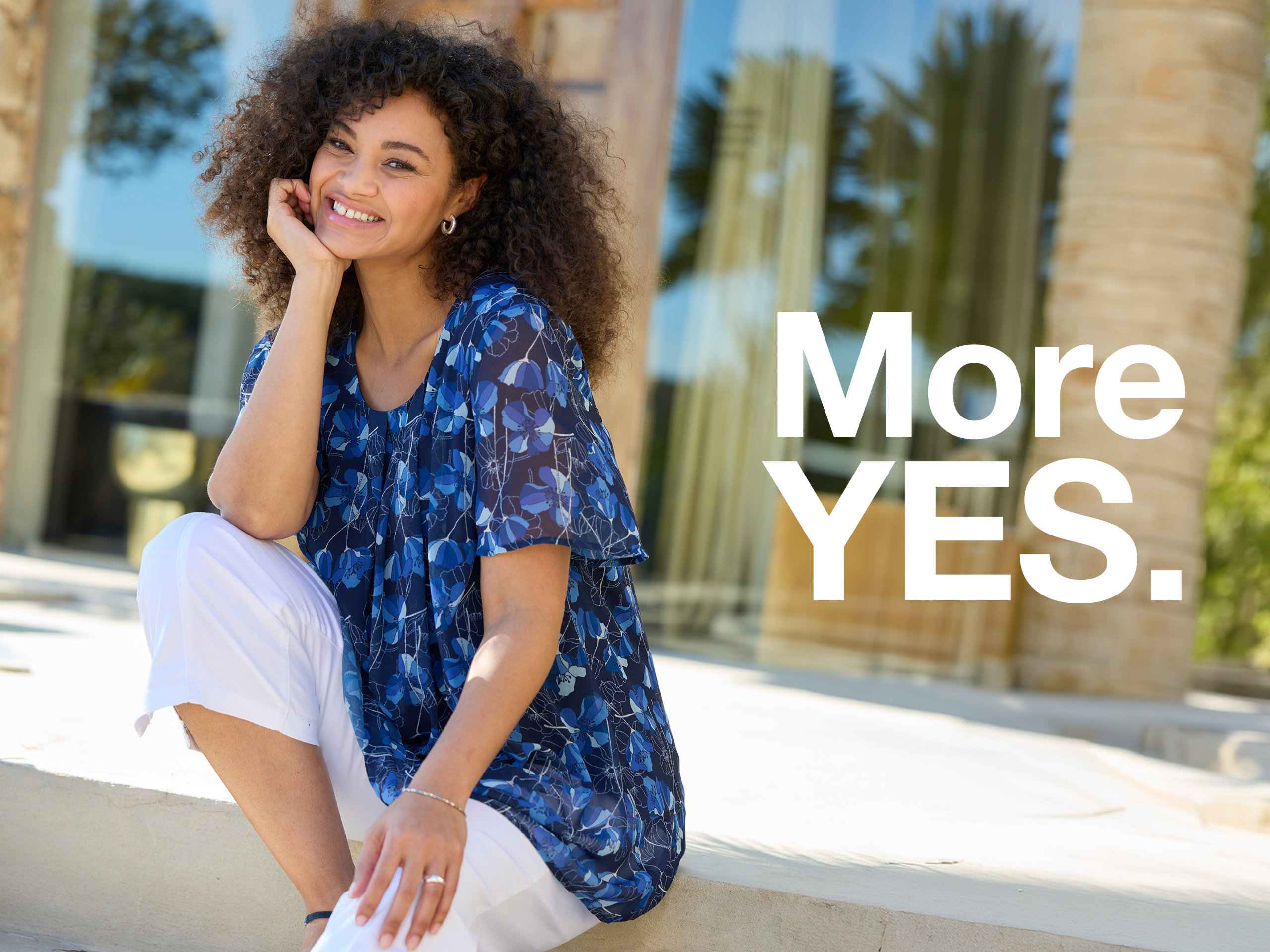 Werbebanner mit Model in floral bedruckter blauer Tunika und weißer 7/8-Hose mit Text More YES.