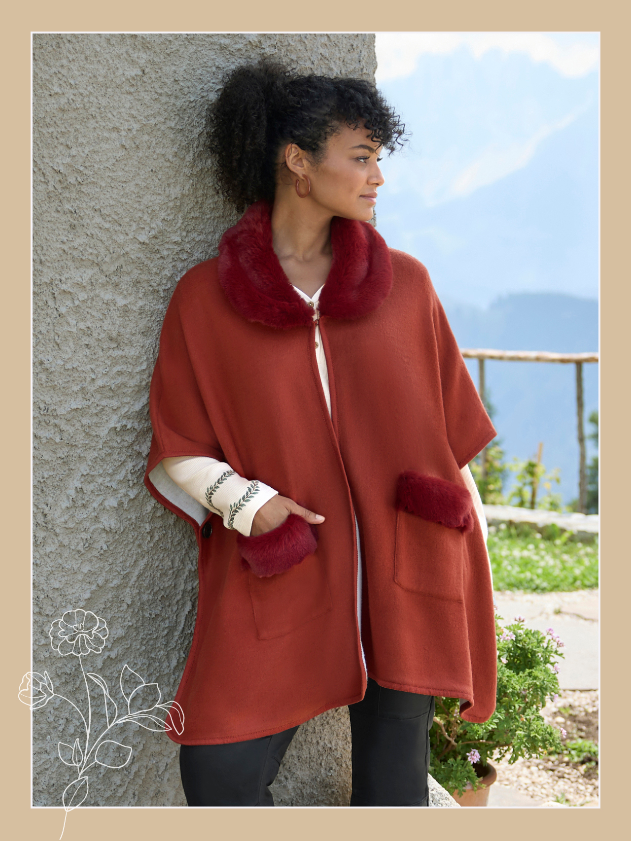 Ein Model trägt ein rostrotes Cape mit Plüschbesatz an den Ärmeln und am Kragen