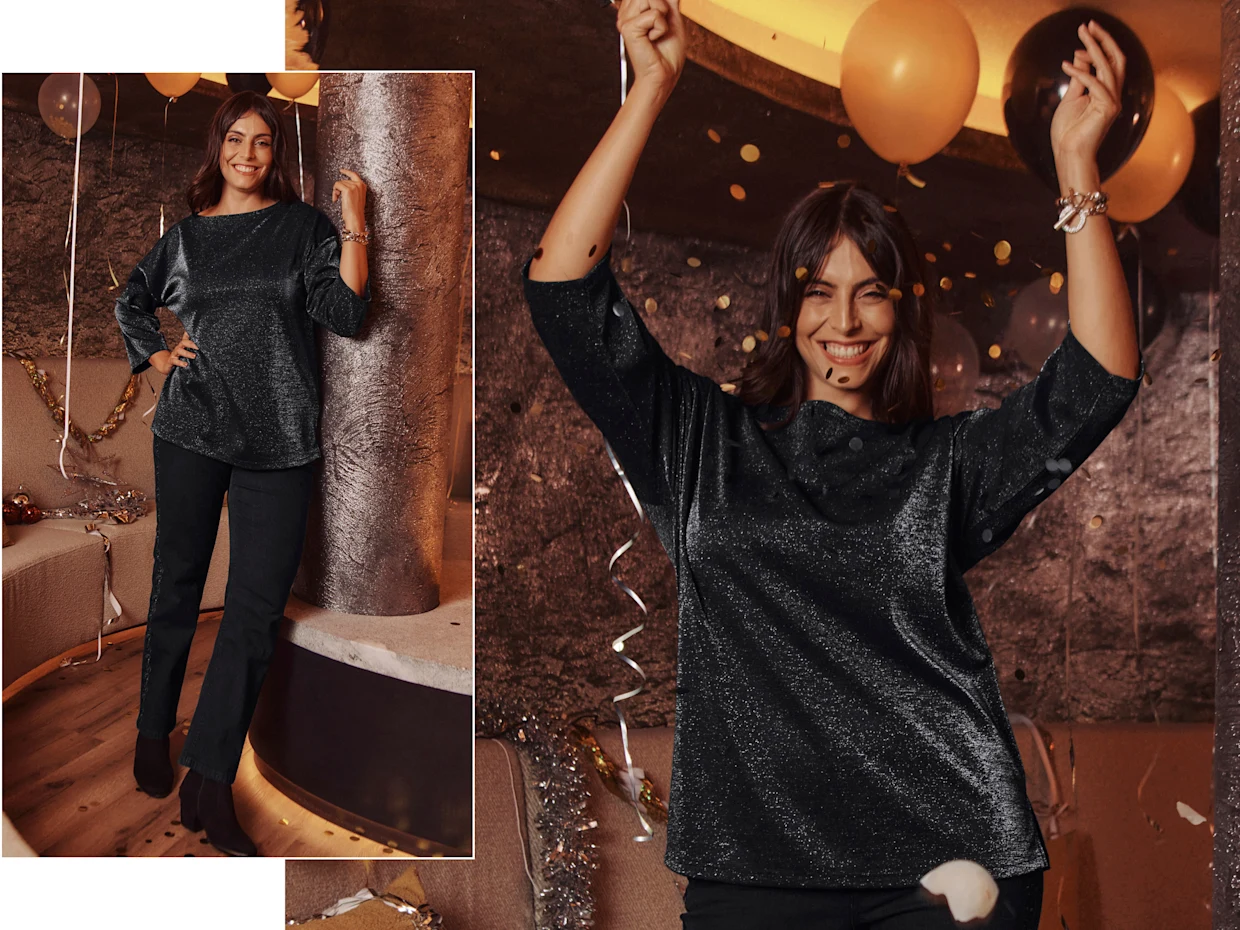 Ein Model in einer einer Party Umgebung trägt ein Sweatshirt mit Glitzergarn und eine schwarze Jeans
mit Blütenstickereien.