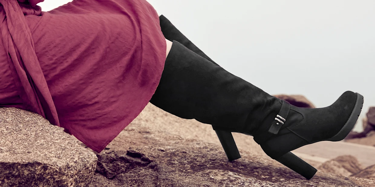 Werbebanner mit Nahaufnahme eines hohen schwarzen Weitschaftstiefel zum Kleid