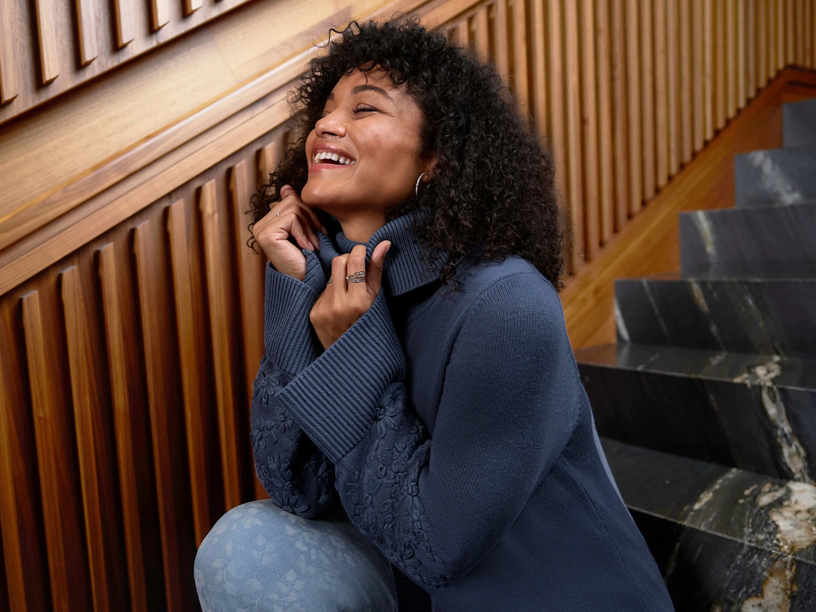 Ein Model trägt einen rauchblauen Rollkragenpullover mit Stickereien am Ärmel und eine blue bleached Bootcut-Jeans mit Laserprint-Blüten. Ein Model trägt einen rauchblauen Rollkragenpullover mit Stickereien am Ärmel und eine blue bleached Bootcut-Jeans mit Laserprint-Blüten.