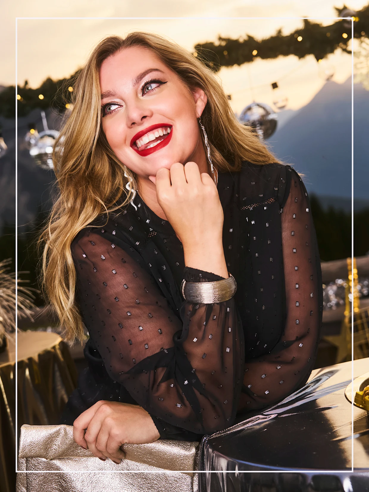 Model in schwarzer Bluse mit Glitzersteinchen und halbtransparenten Chiffon-Ärmeln