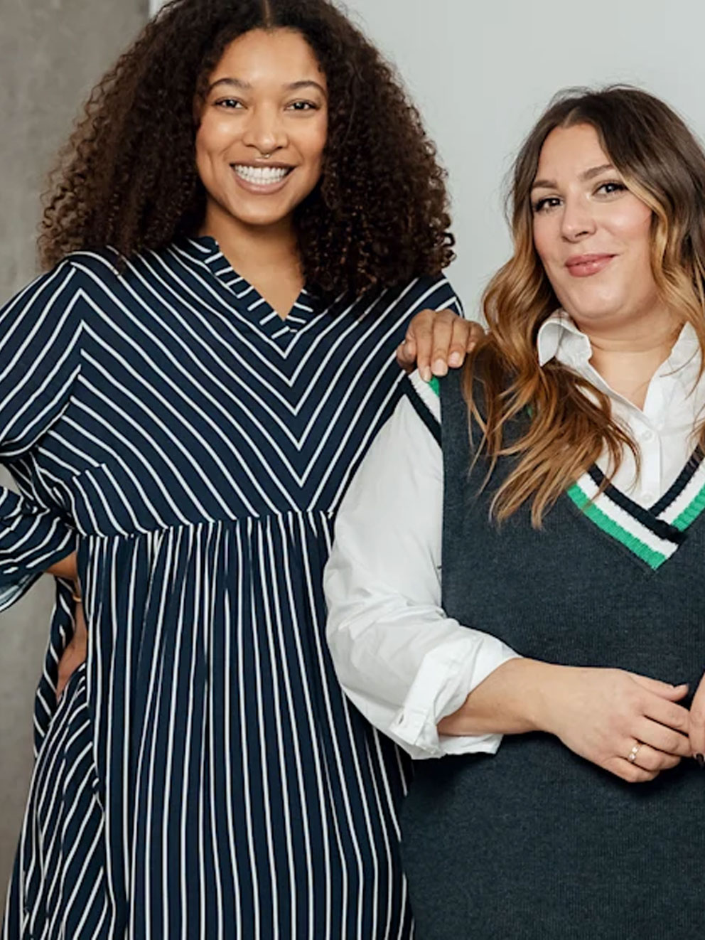 Linke Frau trägt ein Kleid, Rechte Frau steht beratend zur Seite