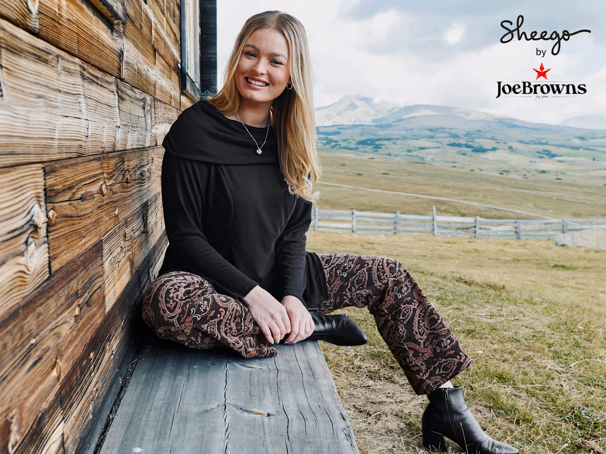 Werbebanner mit Model in schwarzem Pulli und rotbraun-schwarz bedruckter Samthose von Joe Browns Werbebanner mit Model in schwarzem Pulli und rotbraun-schwarz bedruckter Samthose von Joe Browns